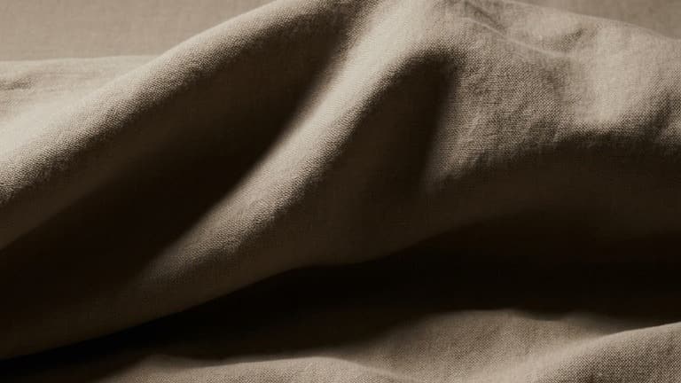 Warm stone linen rumpled into dunes, one bold fold crossing the frame