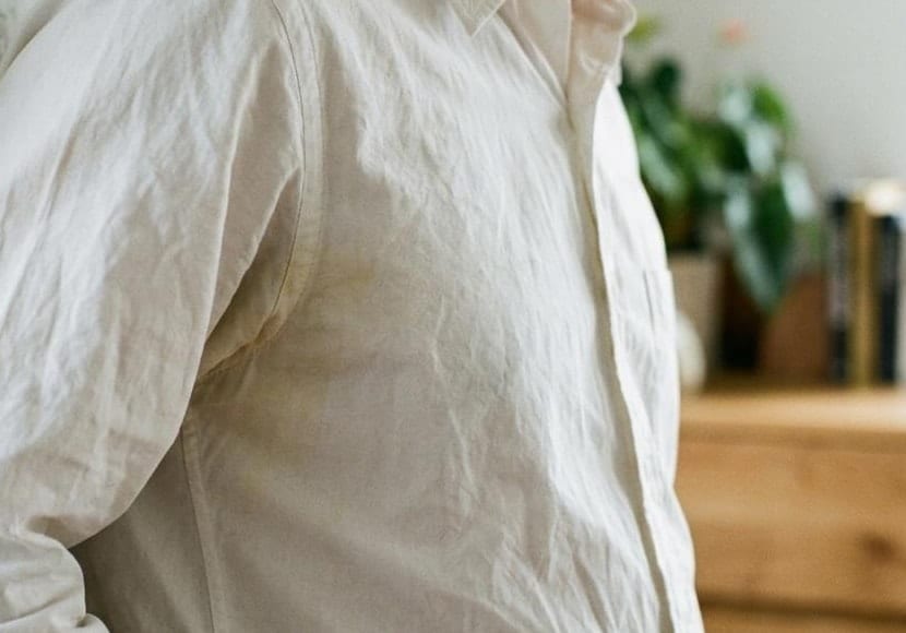 A close view of a cream shirt, a yellow mark spreading out from the underarm seam across the side